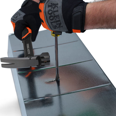 Action shot of a professional wearing Klein Tools safety gloves using a hammer to strike the demolition driver to slit a section of galvanized metal ductwork.