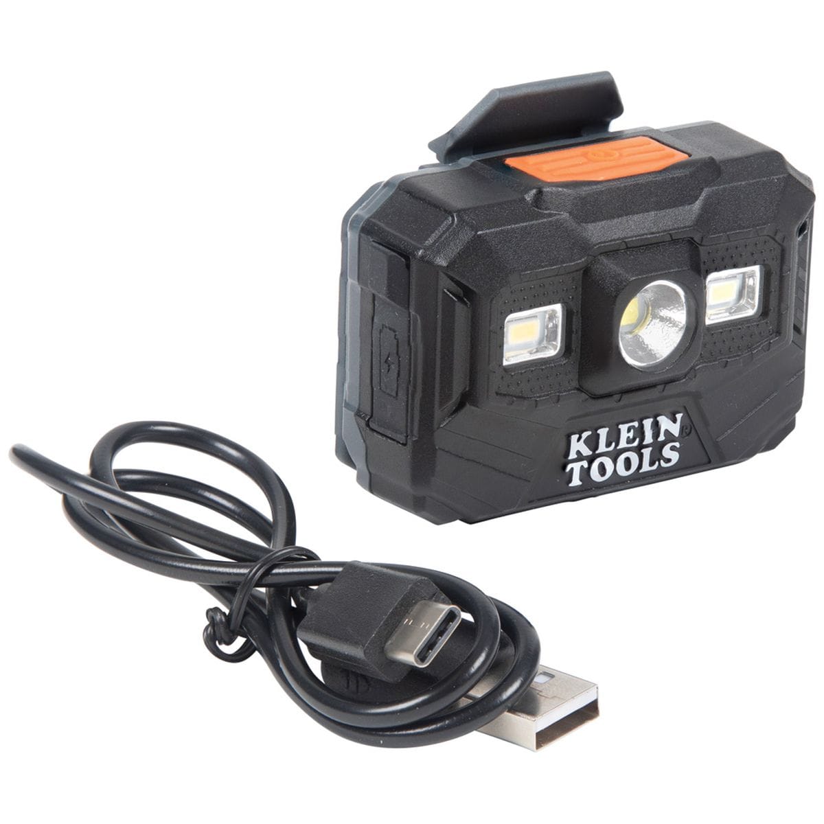 A close-up studio shot of the Klein Tools rechargeable LED headlamp and work light, showing the compact black housing with an orange power button and the included black USB charging cable used for the professional safety helmet system.