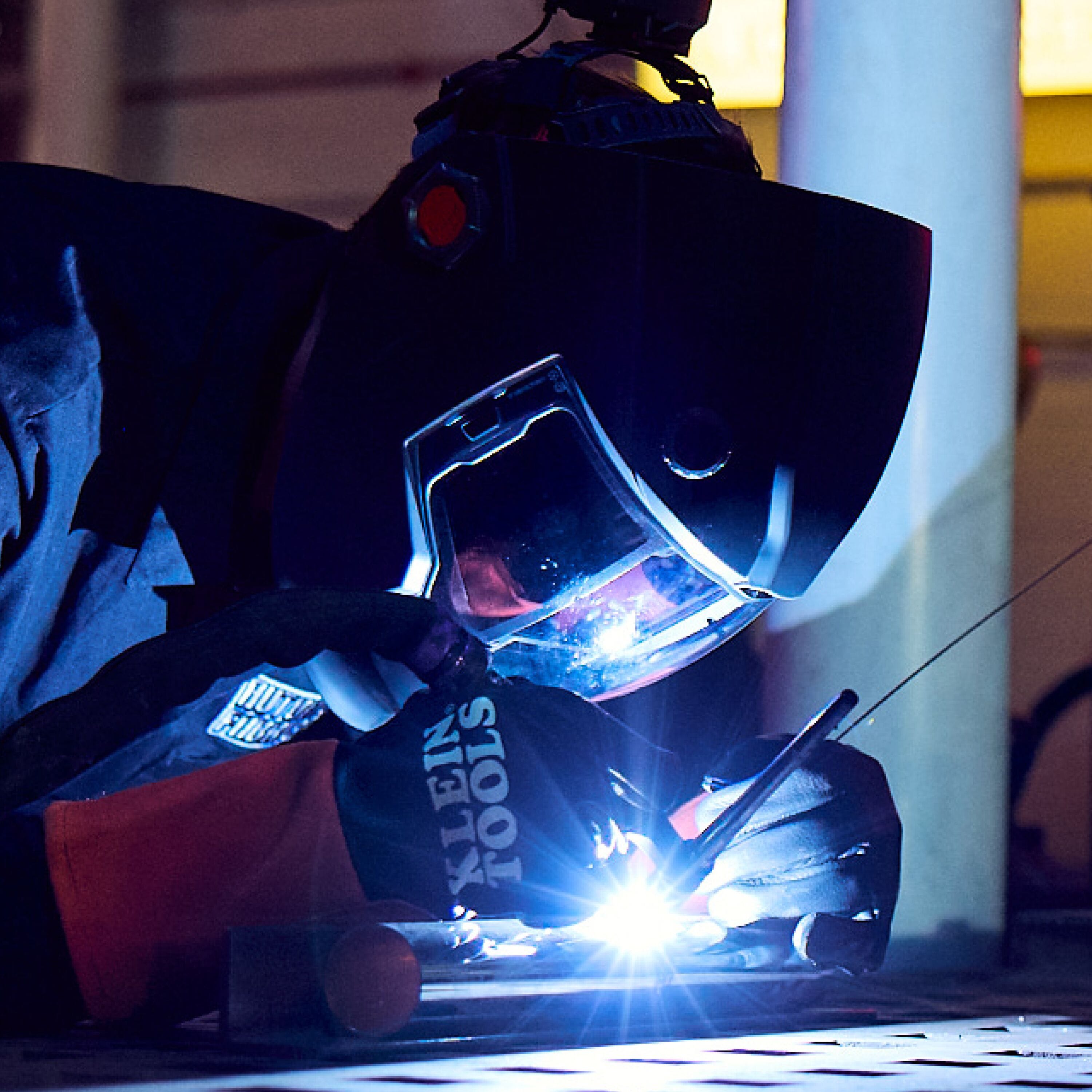 Person welding with protective gear in a workshop setting