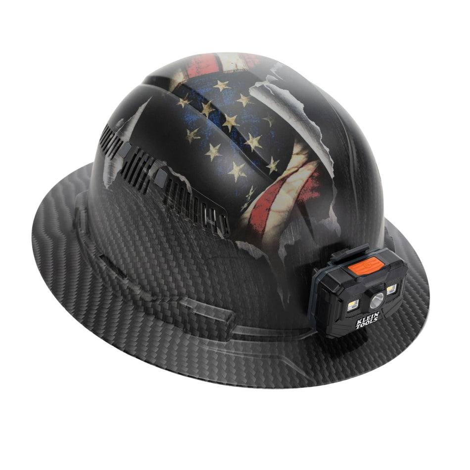 Perspective view of the Klein Tools 60347FS Class C vented full brim hard hat with hydro-dipped KARBN US Flag design and front-mounted rechargeable LED headlamp.