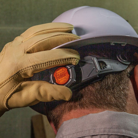 A close-up of the rear ratchet adjustment knob being operated by a gloved user, demonstrating the ease of one-handed sizing adjustments.