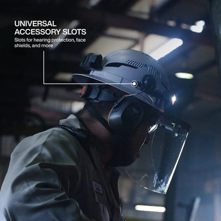 Lifestyle view of a worker wearing the hard hat, demonstrating the universal accessory slots holding a face shield and hearing protection.