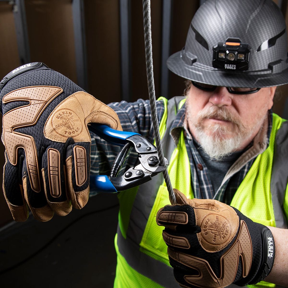 An action shot of a professional in safety gear using the 63016 heavy-duty shears to cut through a thick vertical steel cable, demonstrating the tool's high-leverage shearing power and tactical control.