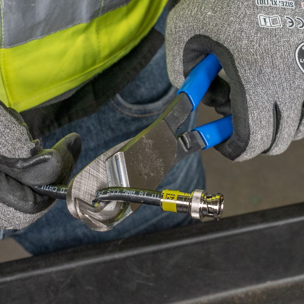 A close-up application photo demonstrating the zero-compression cutting capability of the 63030, showing the blades effortlessly slicing through heavy-duty coaxial cable while maintaining the cable's circular integrity.