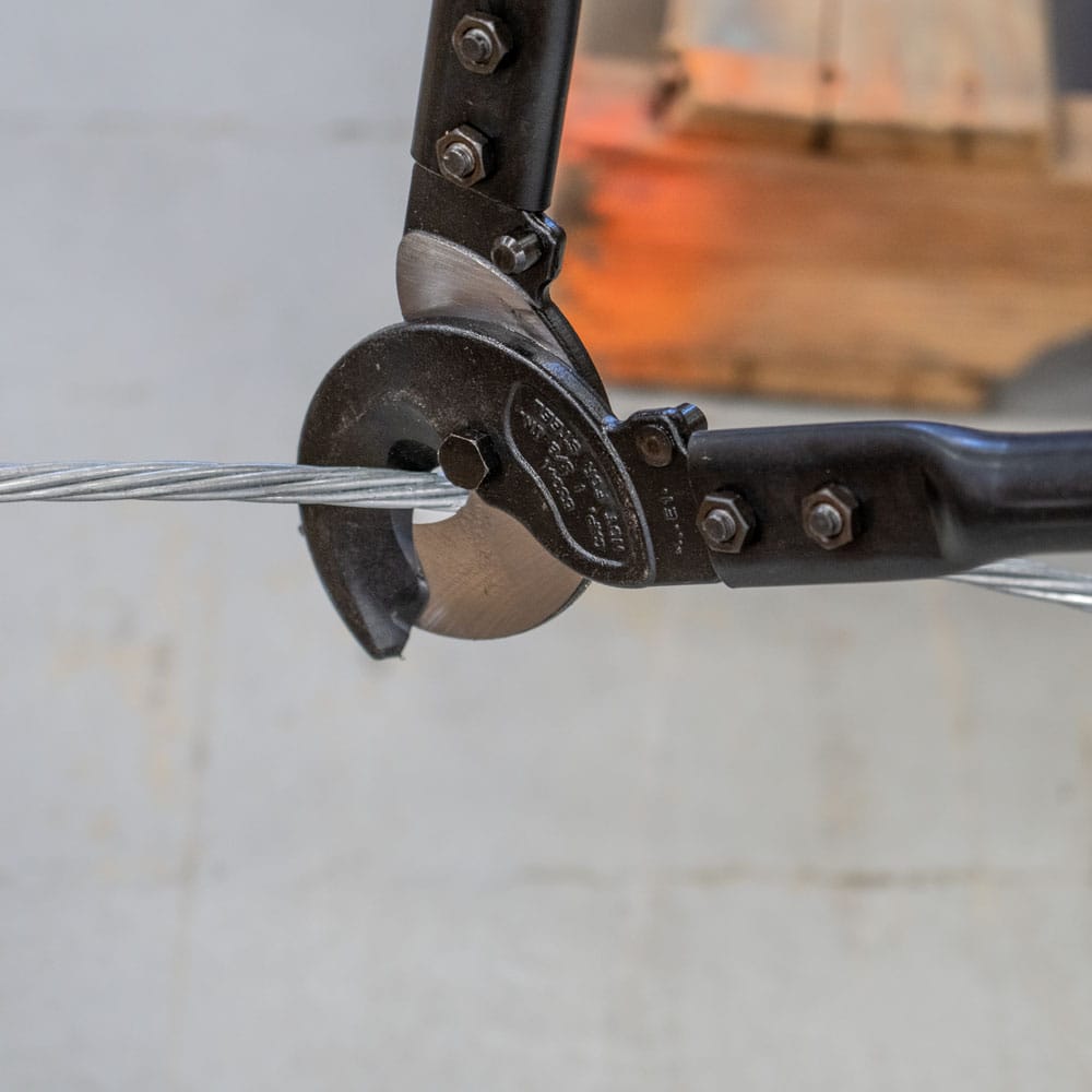 Close-up perspective of the shear blades as they engage a large aluminum cable, demonstrating the high-leverage mechanical advantage and clinical accuracy of the 63041 for utility and industrial cable management.