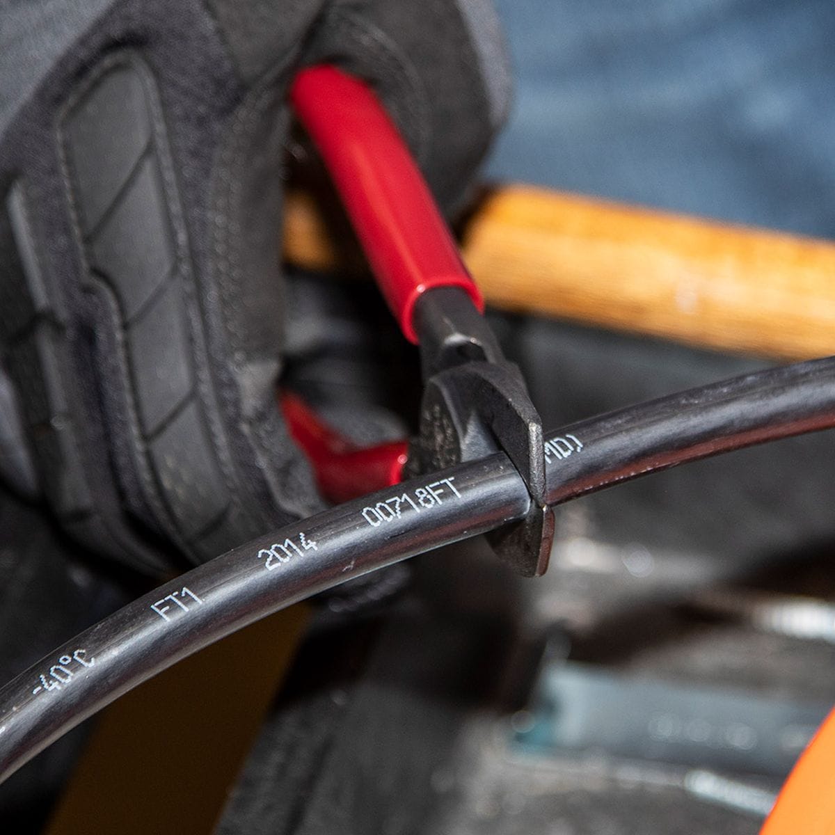 An action shot of the 63215 cable cutter engaging a black conductor, highlighting the precision-ground shear blades and the high-leverage pivot designed for effortless wire preparation.