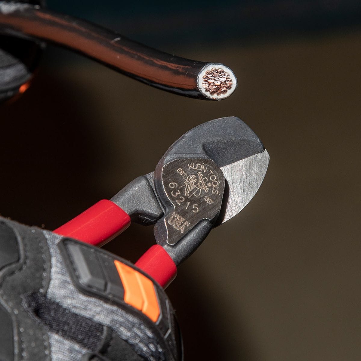 A detailed application photo showing the precision-ground shear blades of the 63215 compact cutter as they sever a small insulated conductor, highlighting the clinical accuracy and burr-free finish.