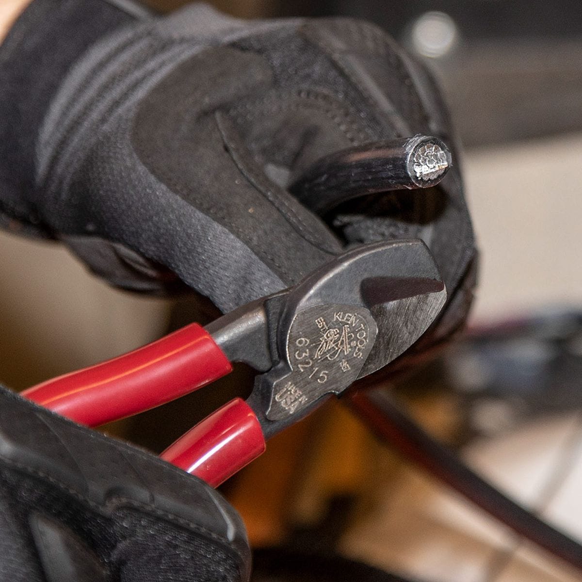 A close-up application photo showing the clean, burr-free end of a thick copper cable after being severed by the Klein Tools 63215 compact high-leverage cutter.