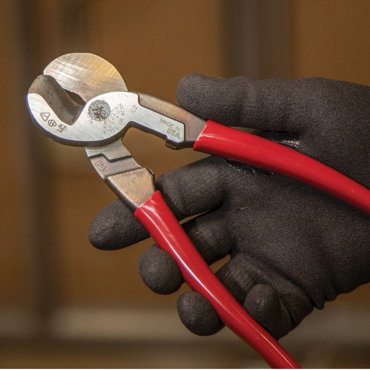 A close-up application photo of a gloved hand holding the 63225 high-leverage cutter, demonstrating the balanced design and tactical control provided by the ergonomic handles.