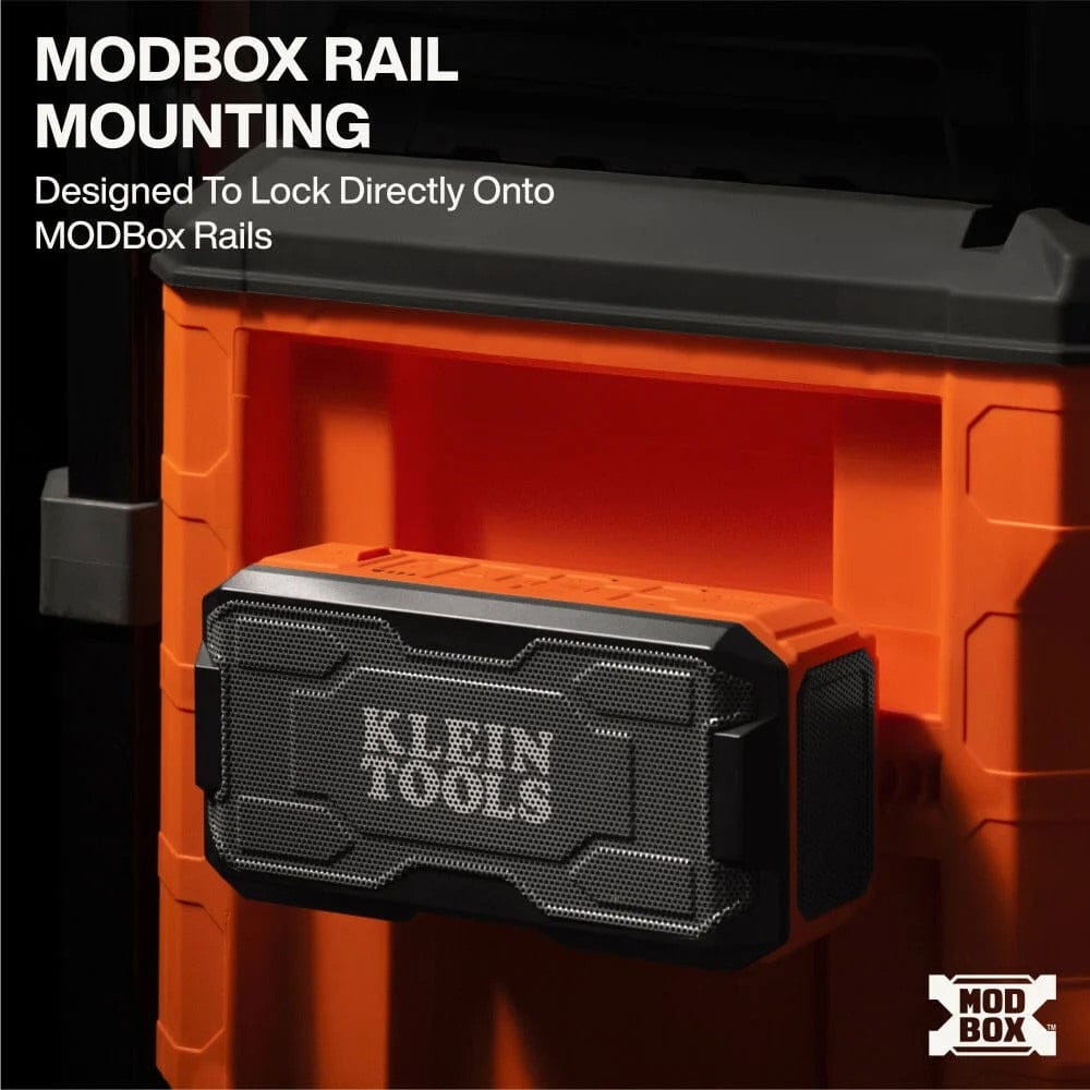 Close-up view of the speaker securely locked onto the side rail of an orange MODbox tool storage system using the rail mounting feature.