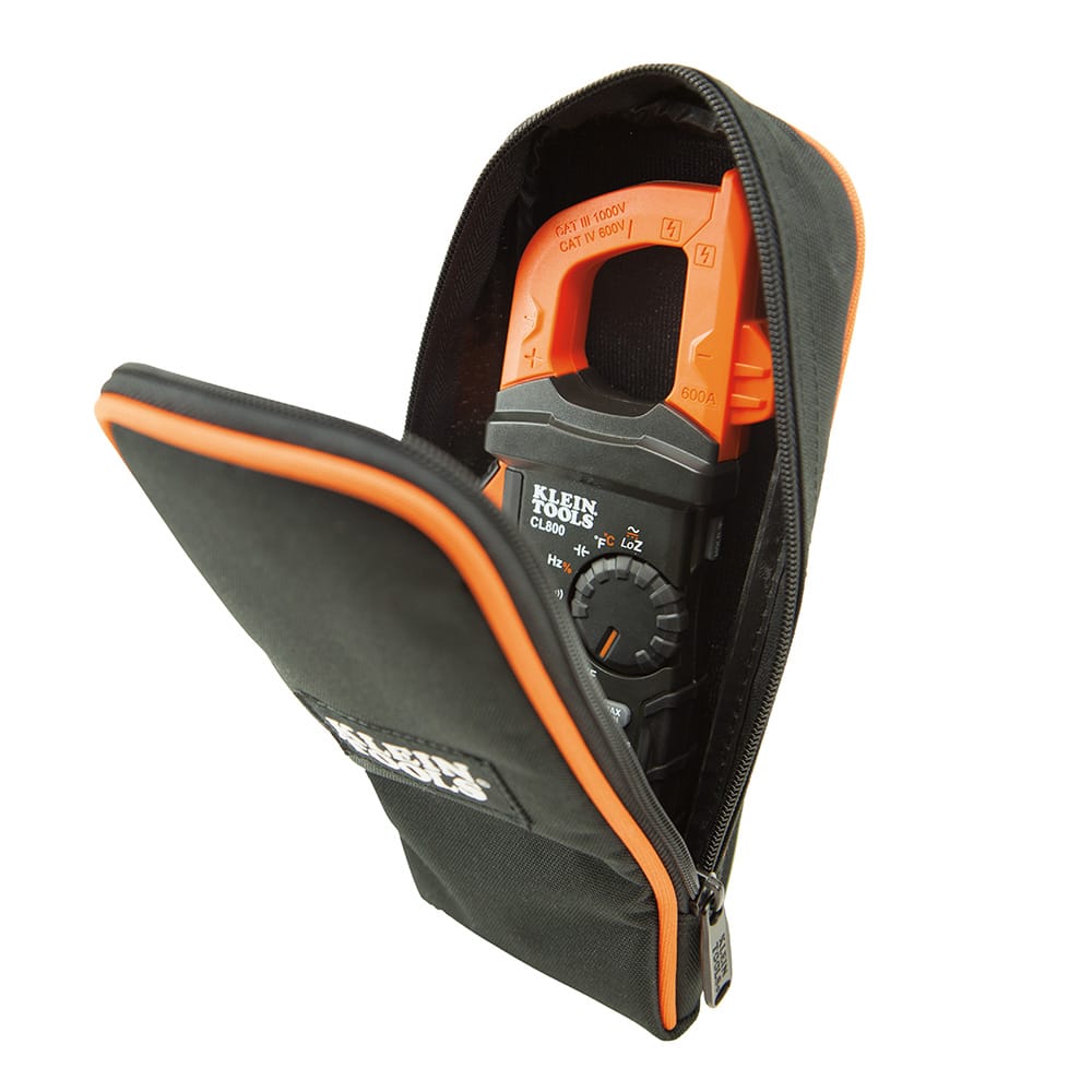 Action shot showing a Klein Tools digital clamp meter and its test leads being stored inside the 69401 carrying case. The image demonstrates the case's capacity to organize and protect sensitive diagnostic instruments from jobsite debris.