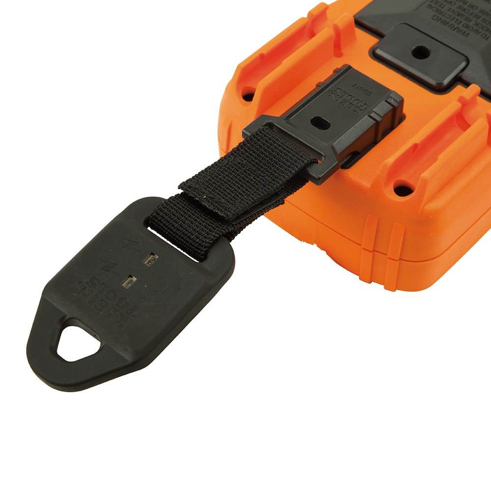 Close-up detail showing the 69417 hanger clip securely snapped into the back of a Klein Tools multimeter rubber boot. The image illustrates how the nylon strap and Velcro loop create a dependable connection between the magnetic mounting plate and the test instrument.