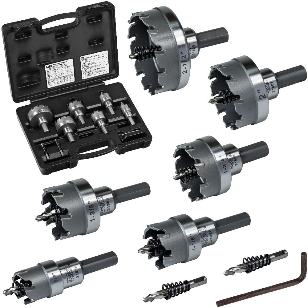 The image shows a set of metal hole saws and drill bits arranged on a white surface, with a black plastic carrying case open on the left.  The hole saws are circular with serrated edges and various sizes, each attached to a cylindrical shaft.  Two drill bits and a small metal tool are also visible at the bottom right.  The image is framed within a black border.