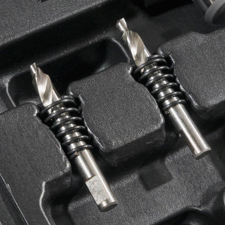 A close-up showing the two extra pilot bits with ejection springs resting in their molded slots in the carrying case.