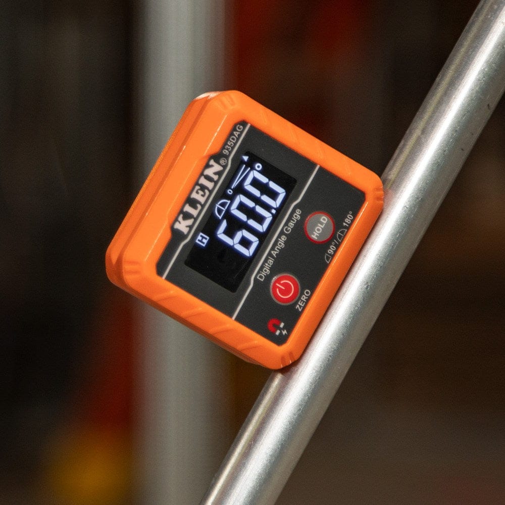 The digital angle gauge magnetically attached to a silver metal conduit pipe bent at an angle, displaying a measurement of 60.0 degrees.