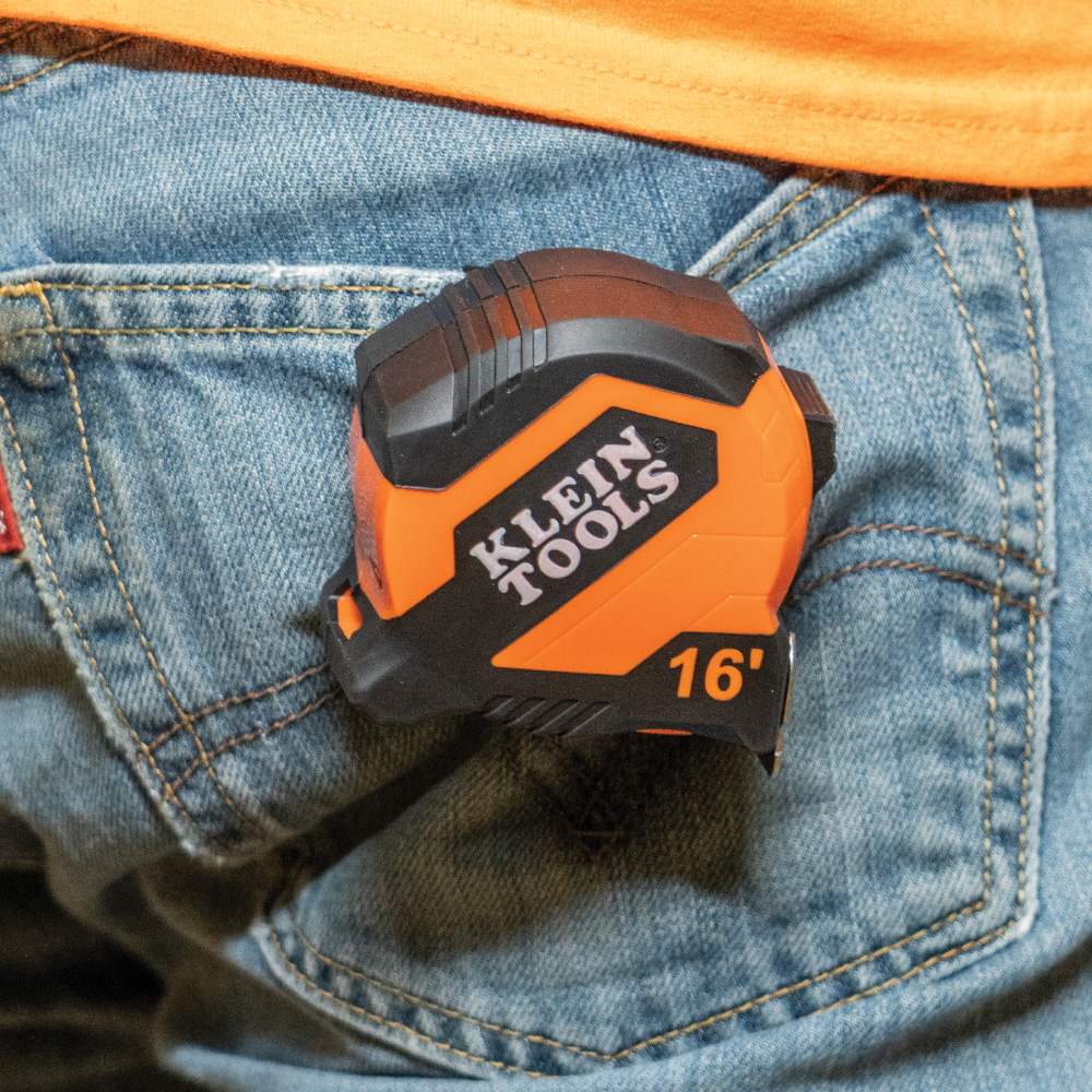 A worker carrying the compact Klein Tools 16-foot tape measure clipped conveniently to their jeans pocket for quick access.