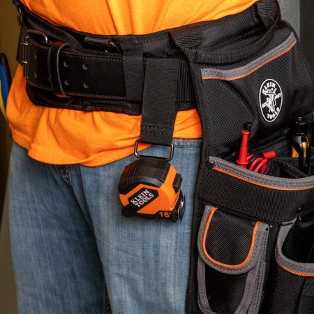 Action shot of the Klein Tools compact tape measure securely attached to a professional tool belt using the integrated metal belt clip.