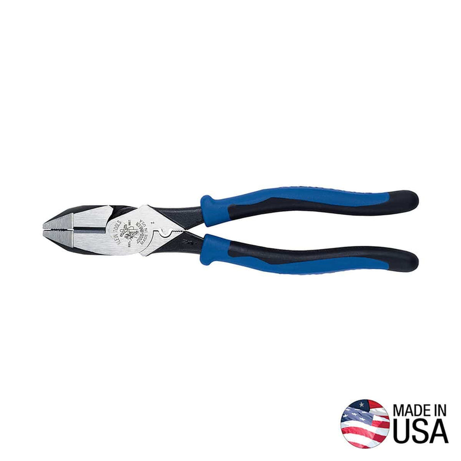 A horizontal studio view of the Klein Tools J2000-9NEC 9 inch high leverage linesman pliers featuring a polished steel head with a built-in connector crimping die, black oxide coated alloy steel body, and ergonomic blue and black dual material Journeyman cushion-grip handles alongside a circular Made in USA logo against a white background.