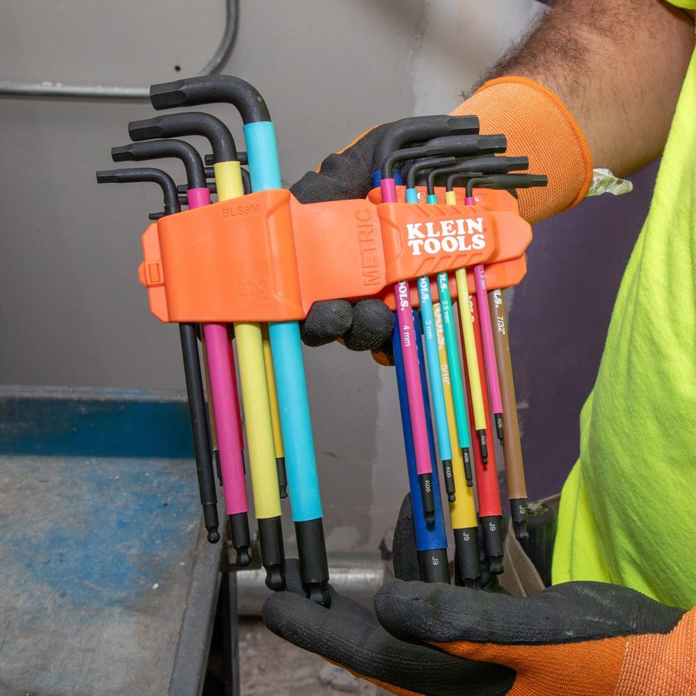 A professional technician in work gloves holding the interlocking SAE and metric storage caddies from the Klein Tools 18-piece hex key set for easy portability.