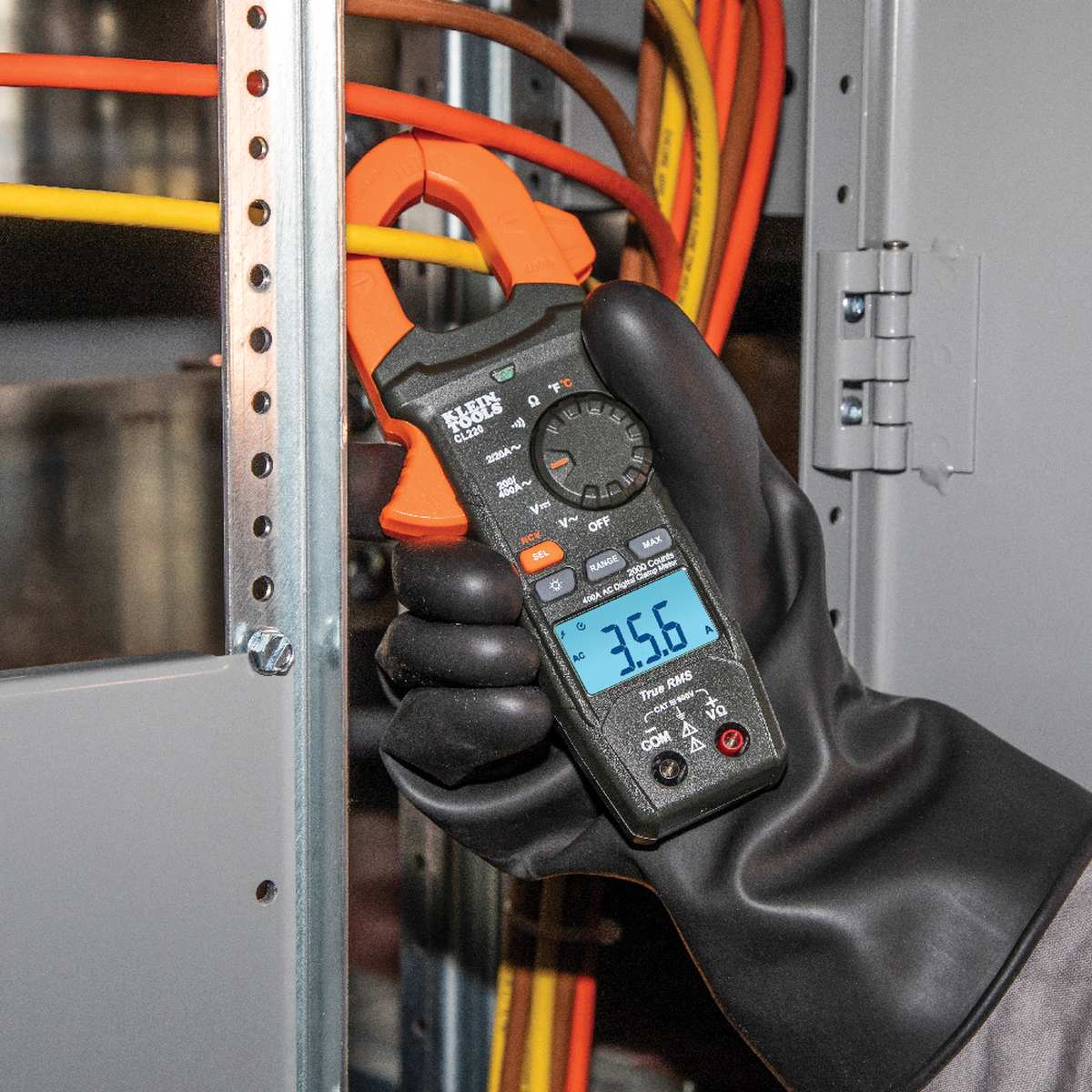 Action shot of a technician using the CL220 to measure AC current in a residential HVAC unit. The clamp jaw is shown encircling a live wire, while the high-contrast backlit LCD provides a clear real-time reading of the electrical draw in a dimly lit mechanical environment.
