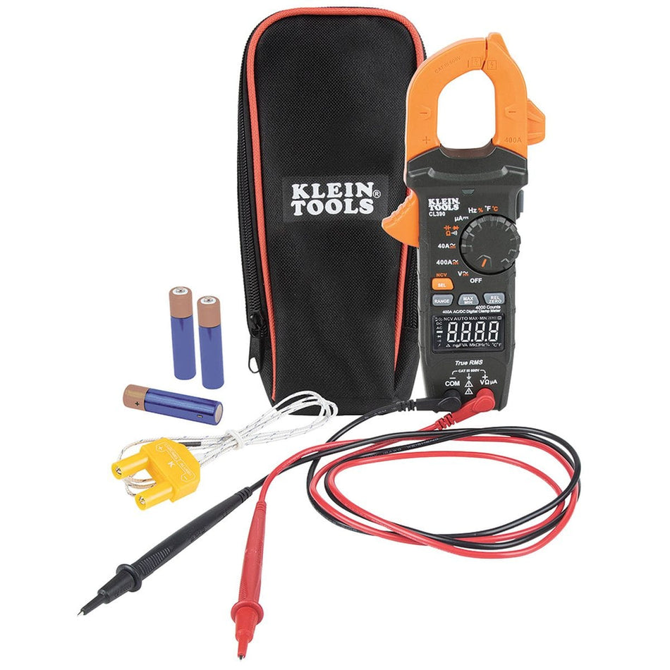 A comprehensive studio kit shot of the Klein Tools CL390 AC/DC digital clamp meter. The package includes the True RMS multimeter with reverse contrast LCD, a set of red and black safety-rated test leads, a K-type thermocouple probe, three AAA alkaline batteries, and a heavy-duty black and orange zippered carrying pouch.