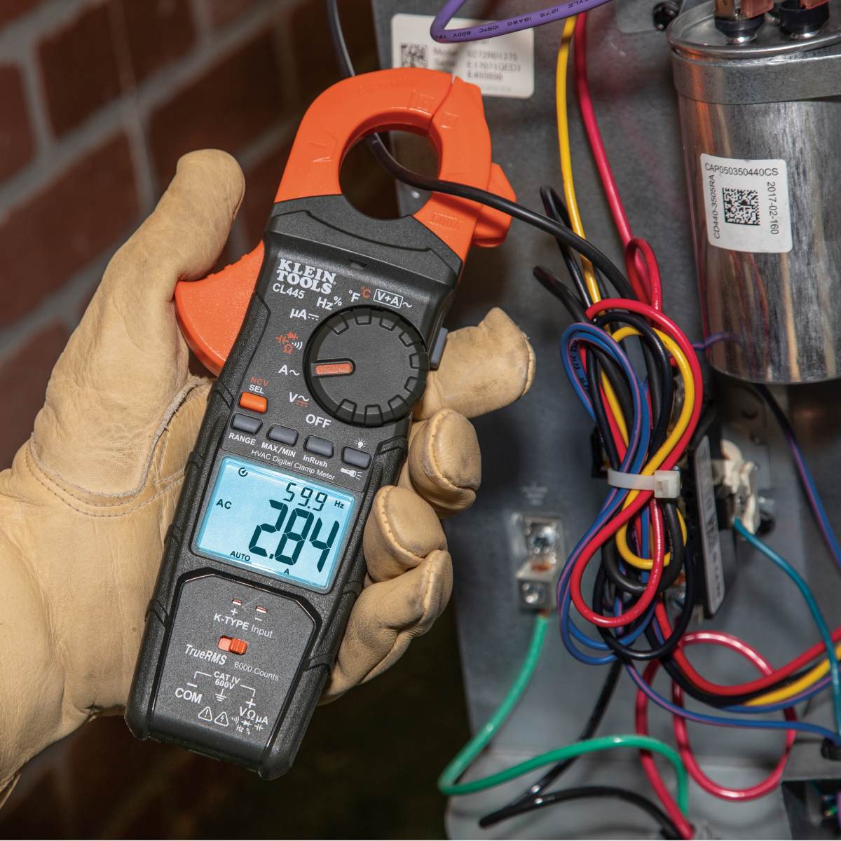 A side profile of the CL445 clamp meter focusing on the integrated LED worklight located beneath the clamp jaw. The light is shown activated, demonstrating its utility for illuminating dark electrical panels and HVAC equipment during troubleshooting.