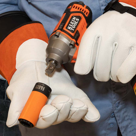 Utility technician in safety gloves mounting an orange-coated 7/8 x 11/16-inch coaxial socket onto a 1/2-inch square impact wrench anvil.