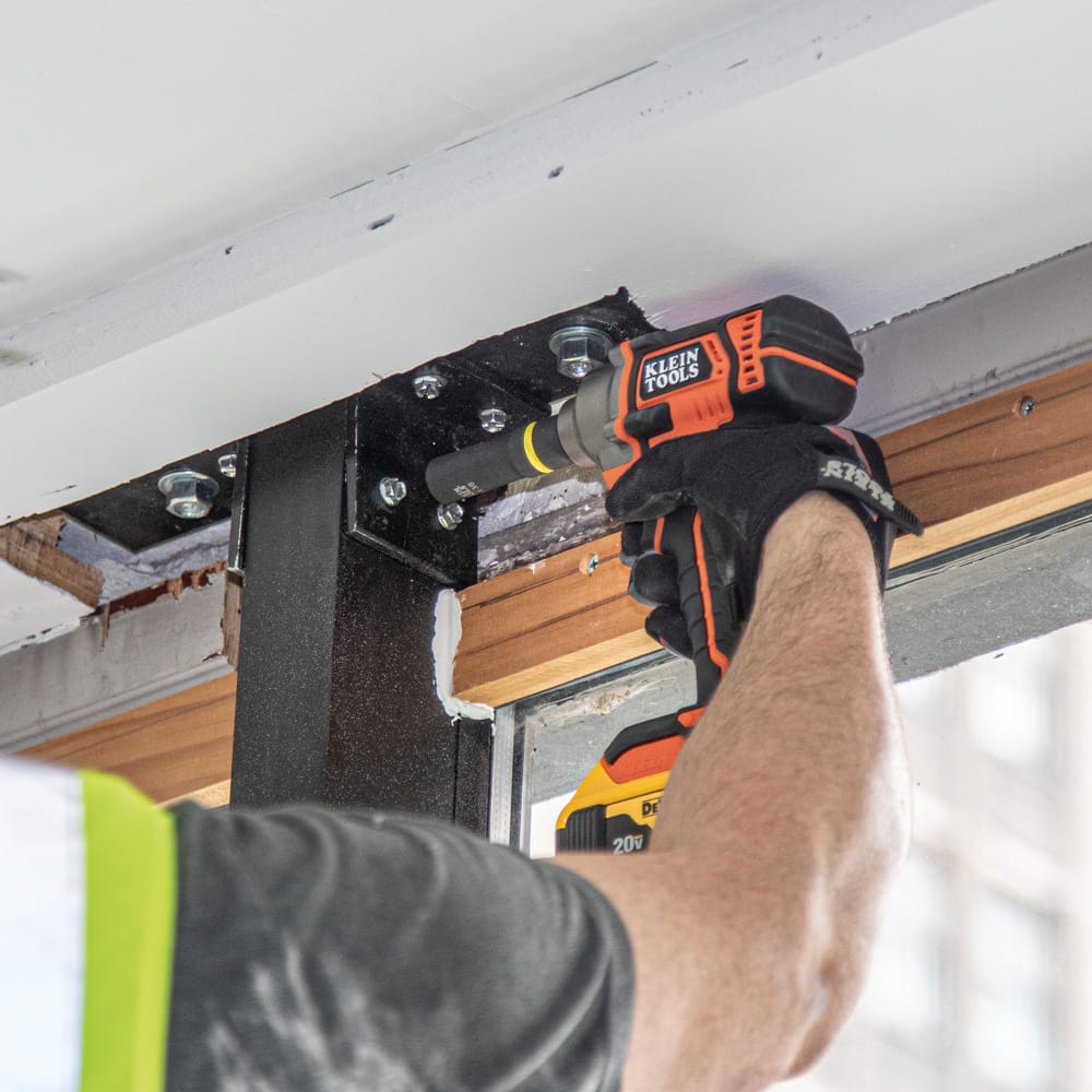 Contractor securing overhead structural bracket hardware using a Klein 12-point spring-loaded coaxial socket on an impact wrench.