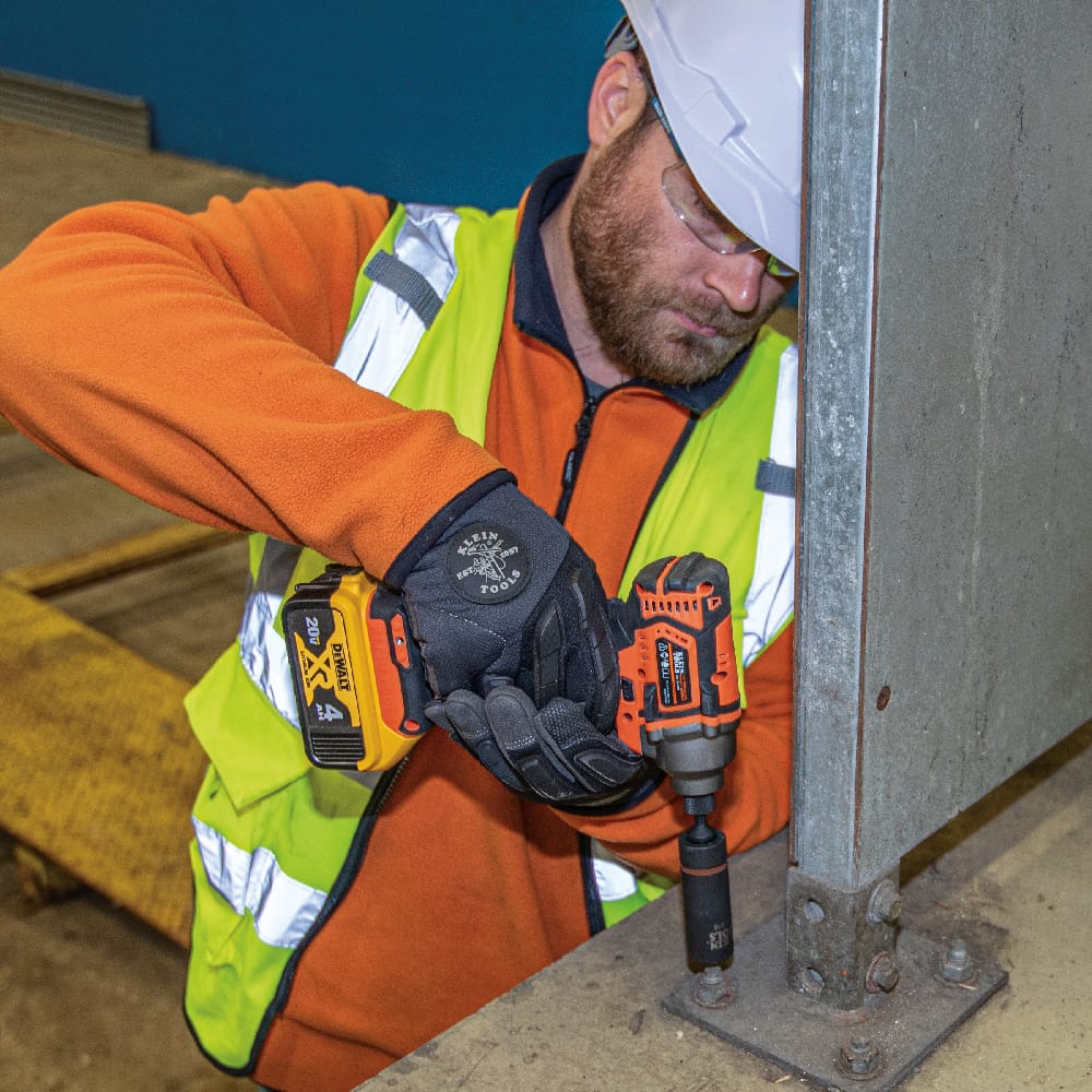 Ironworker in a hardhat using a Klein 24mm by 19mm coaxial impact socket on a power driver to secure structural column mounting plates.