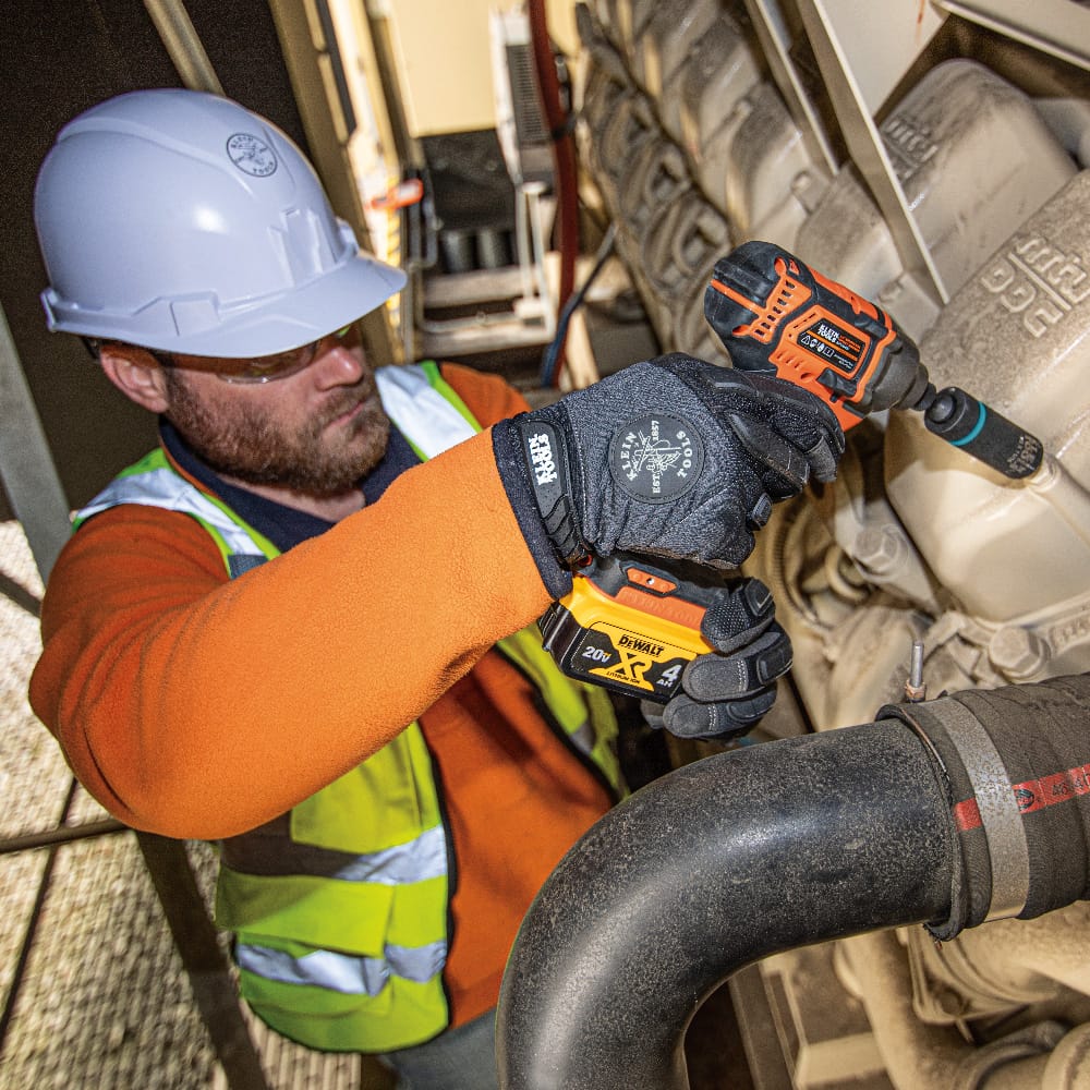 Industrial technician using a Klein coaxial metric socket on an impact driver to tighten engine housing bolts in tight spaces.