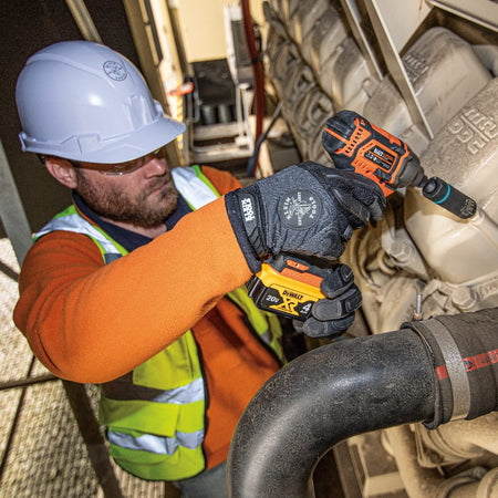 Industrial technician using a Klein coaxial metric socket on an impact driver to tighten engine housing bolts in tight spaces.