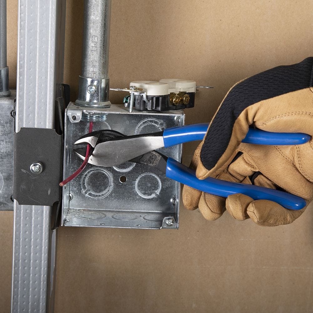 An action shot showing the Klein D2000-48 angled head diagonal pliers cutting an insulated red wire inside a silver metal electrical box, illustrating the tool's effectiveness in narrow, hard-to-reach locations.