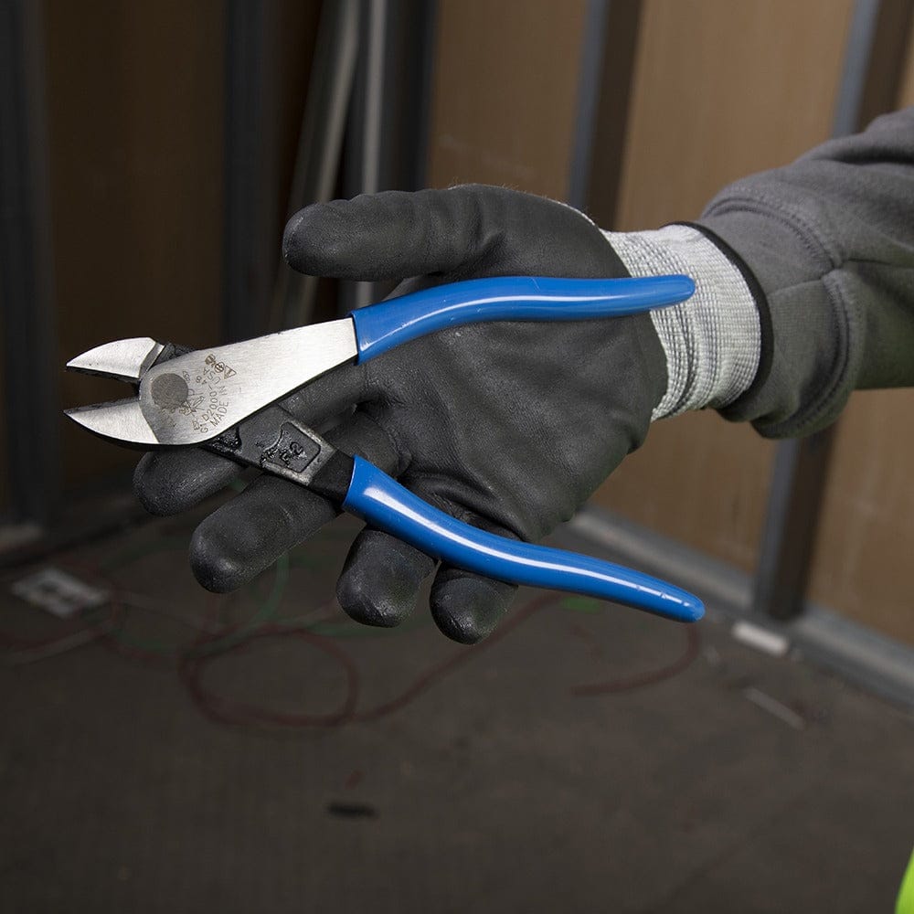 A tradesperson wearing a gray long-sleeve shirt and black work gloves holding the Klein D2000-48 8-inch diagonal cutters, demonstrating the ergonomic size and high-leverage handle design for industrial use.