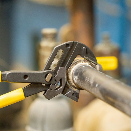 Action shot of the Klein Tools plier wrench utilizing its V-jaw side to grip a round pipe, illustrating the 3-point contact grip designed for plumbing and mechanical work.