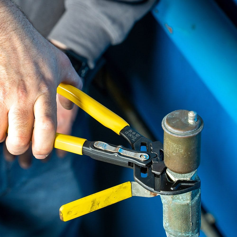 Detailed action shot showing the high-torque grip of a Klein Tools plier wrench on a plumbing valve, demonstrating the tool's effectiveness for heavy-duty mechanical tasks.