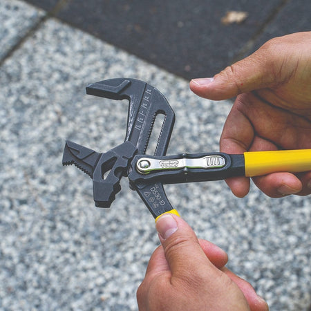 Hands demonstrating the easy push-button adjustment on the 10-inch Klein Tools plier wrench, showing the fast-action mechanism for switching between multiple jaw positions.