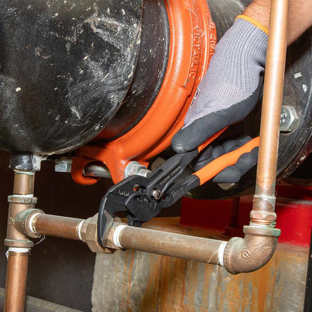 Action shot of a professional using the Klein Tools compact plier wrench to secure a copper pipe fitting, demonstrating its effectiveness in plumbing applications.
