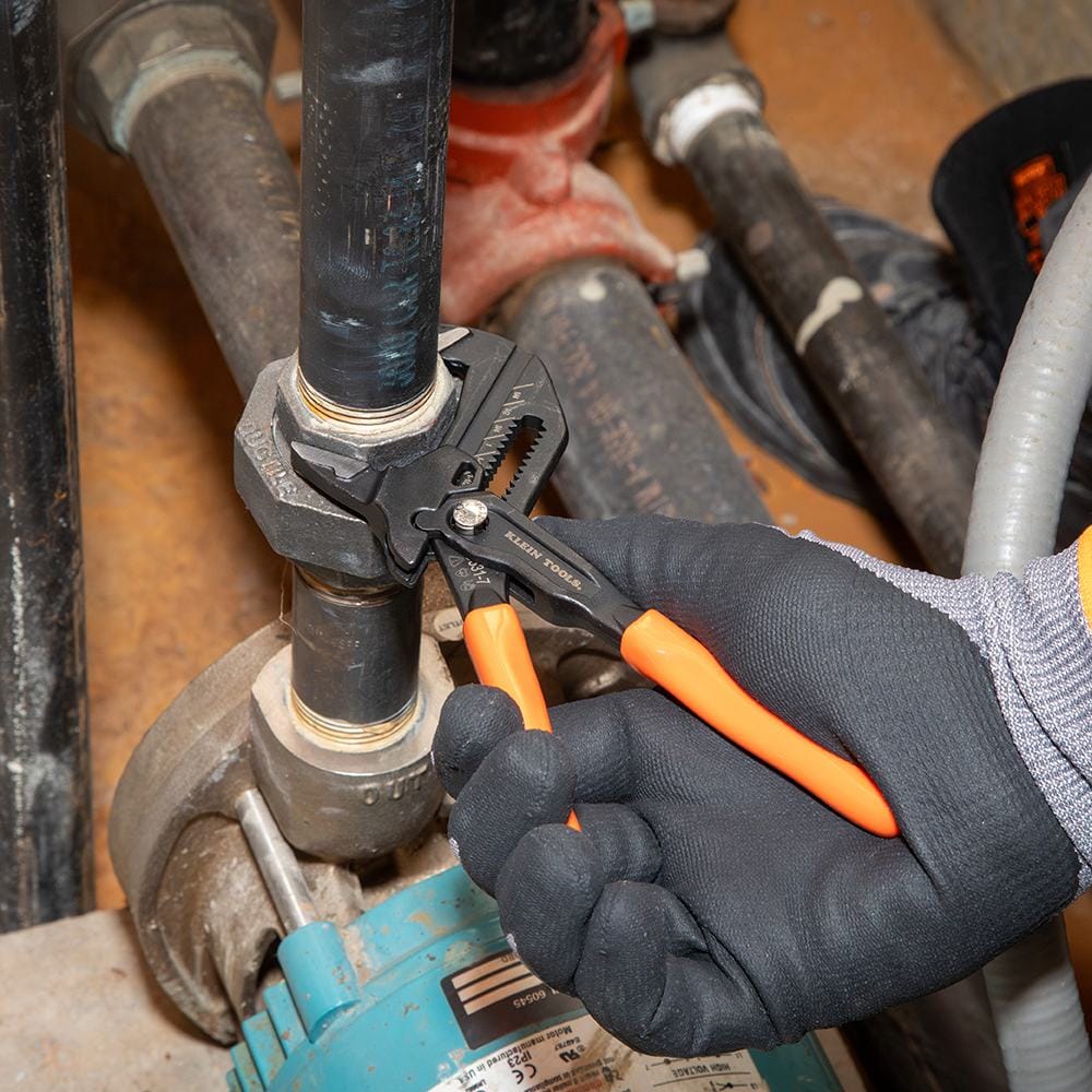 Close-up of a worker using the compact plier wrench to tighten a large hex nut in a cramped industrial setting, demonstrating access in hard-to-reach spaces.