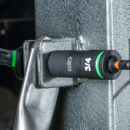 Contractor using a Klein 3/4-inch deep-well impact socket with a 1/4-inch quick-connect adapter to tighten structural machinery bolts.