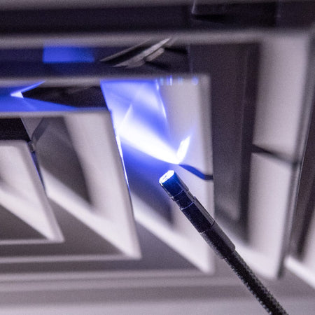 Close-up action shot of the 8mm borescope camera head navigating a metallic vent. The image highlights the intensity of the 6 integrated LEDs, which provide essential illumination for capturing clear diagnostic details in dark, confined spaces.
