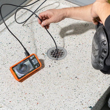 Action shot of a professional technician using the ET19 Pro Borescope to inspect a kitchen sink. The high-resolution 4.3-inch color LCD screen displays a clear 720p HD image of the mechanical components, illustrating the tool's effectiveness for detailed HVAC system diagnostics.