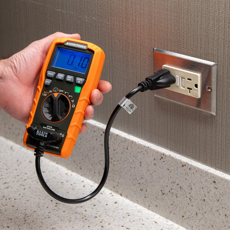 Close-up of the Klein Tools ET270 performing a GFCI trip test on a kitchen or bathroom style receptacle. The user is pressing the dedicated GFCI button, and the high-contrast display shows a trip time of 0.10 seconds, confirming the safety device is operating within specifications.