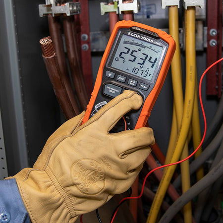 Action shot showing a technician holding the ET600 megohmmeter while diagnosing a large copper conductor in an industrial panel. The meter displays a real-time insulation resistance value of 2534 MΩ, demonstrating the tool's high-sensitivity sensing capabilities.