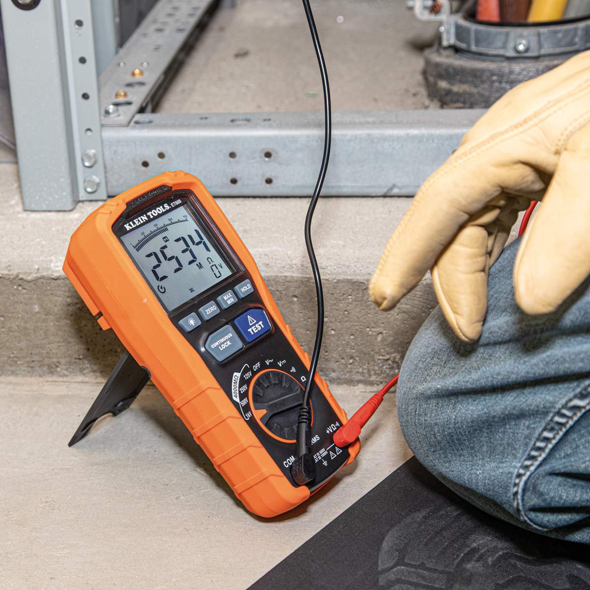 A ground-level application shot of the ET600 tester standing on its kickstand during a field test. The image illustrates the ease of viewing the backlit display from an angle while the technician performs electrical maintenance in a mechanical room.