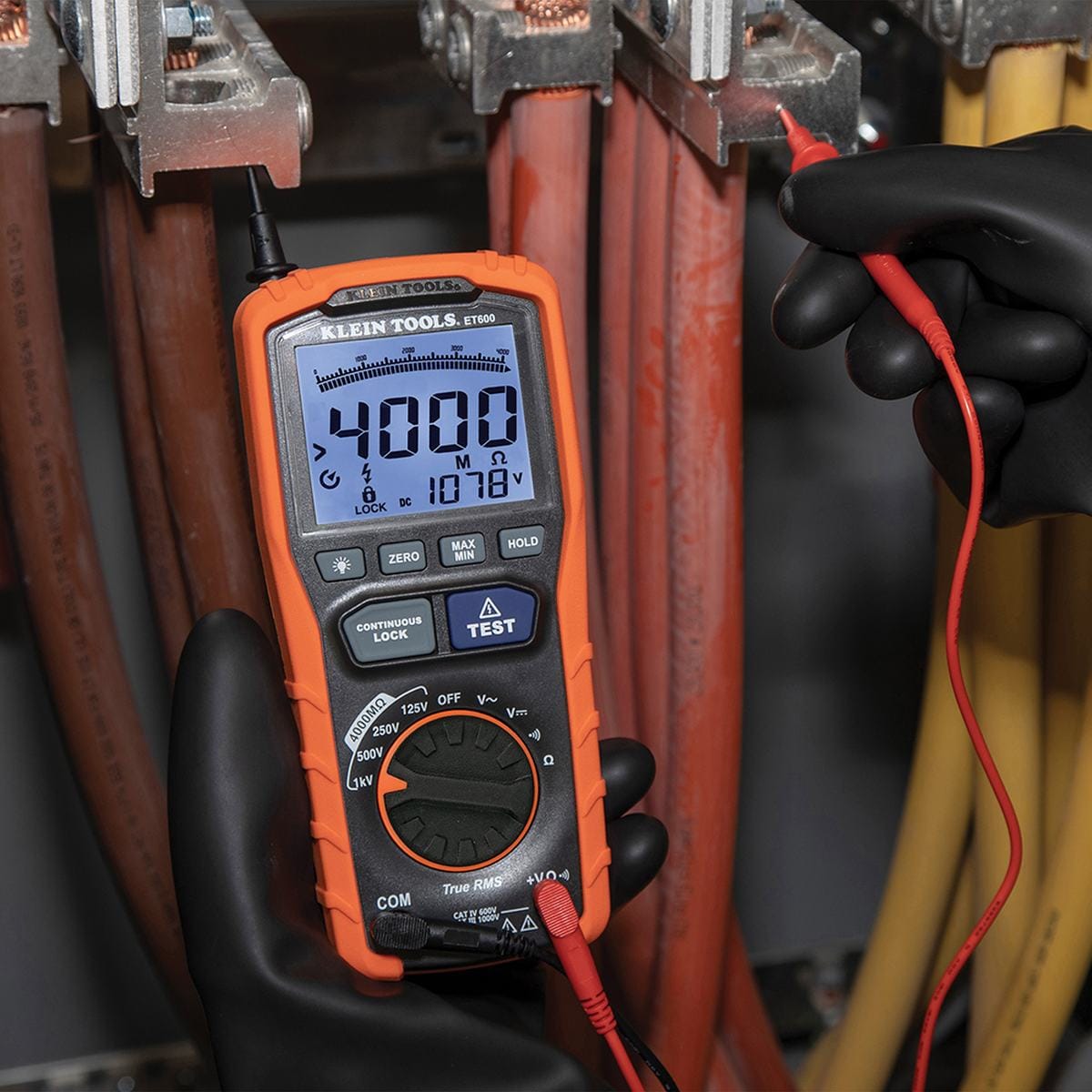 An action shot of a technician wearing high-voltage safety gloves using the ET600 test probe on an industrial busbar. The meter is displaying a resistance reading of 4000 MΩ, proving the maximum range of the insulation resistance testing function.