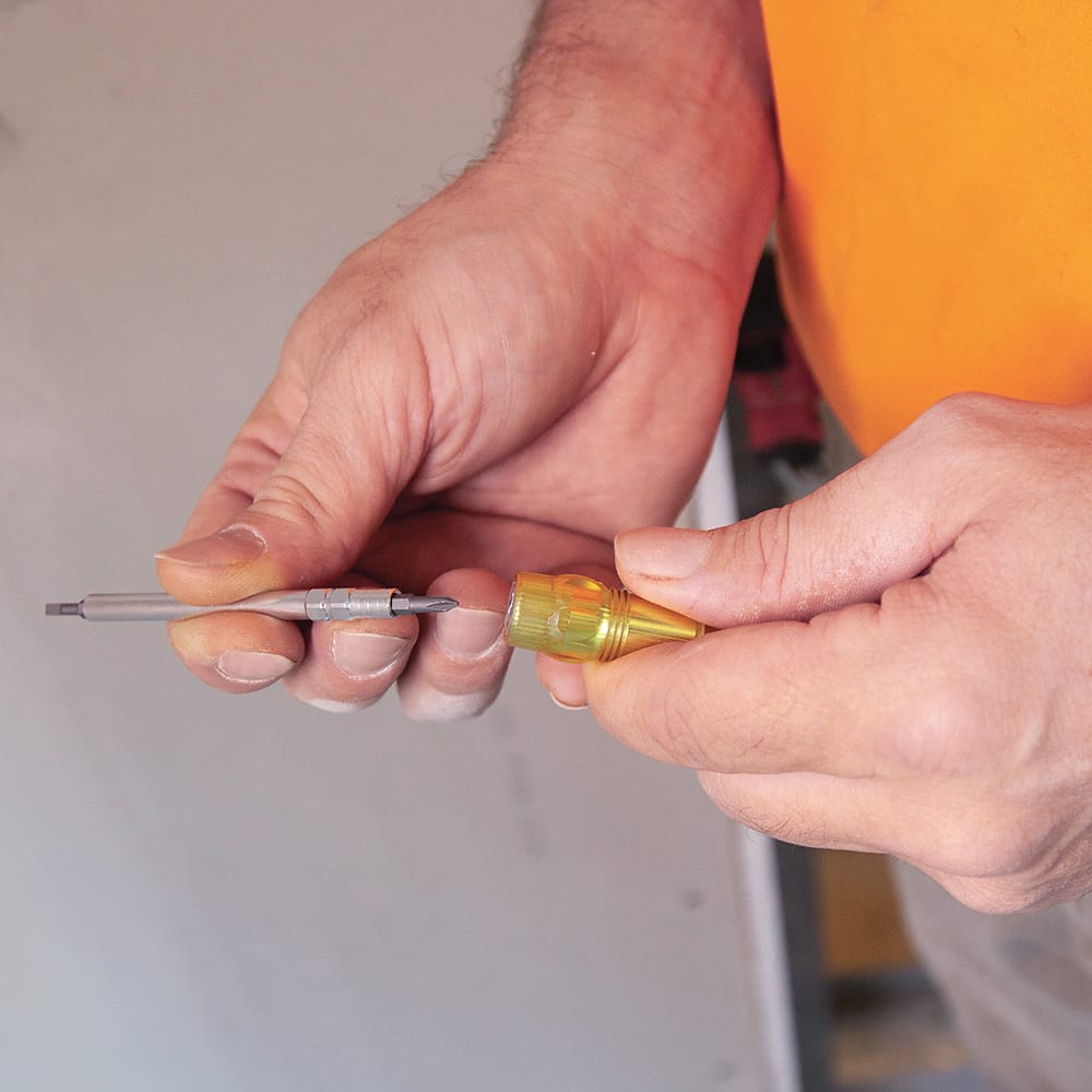 Worker swapping bit orientations on the Klein 32614 precision driver by pulling the double-ended steel shaft out of the aluminum sleeve.