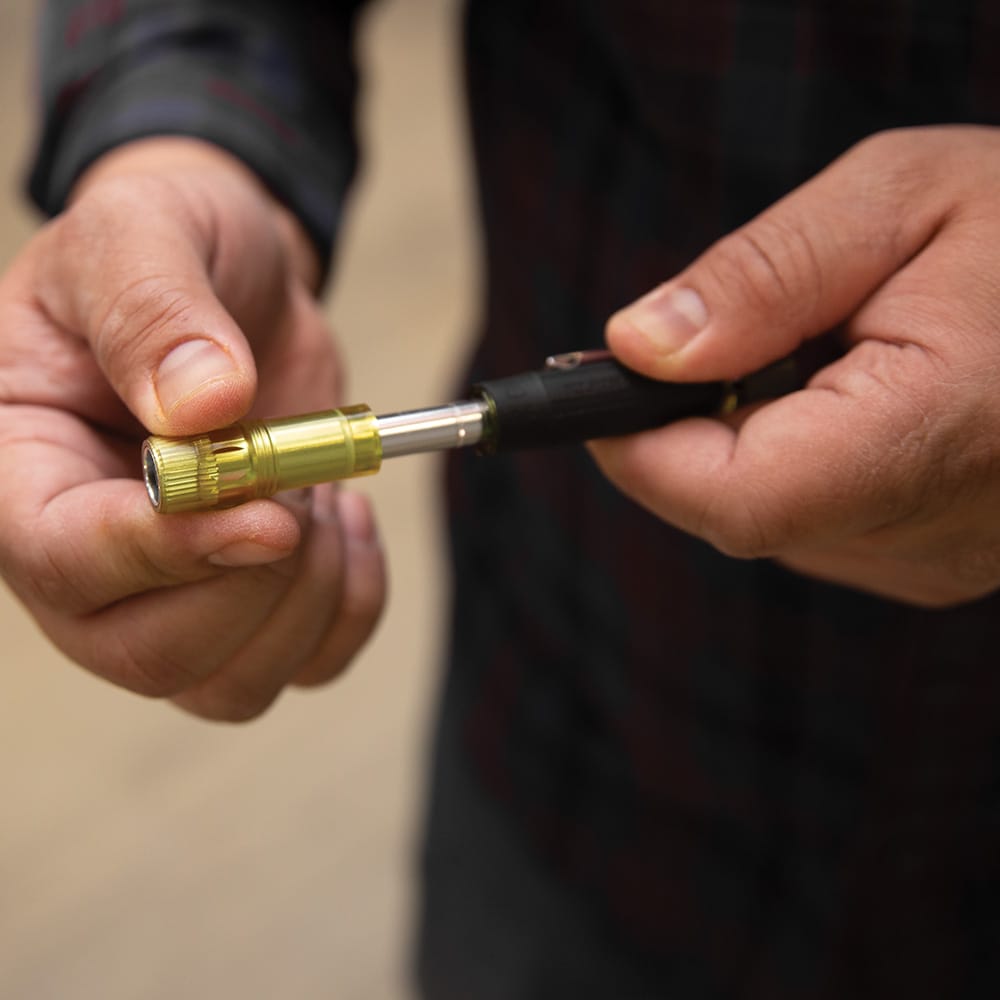 Technician sliding the yellow protective collar forward on a Klein 32614 driver to conceal the metal bit tip for safe pocket storage.