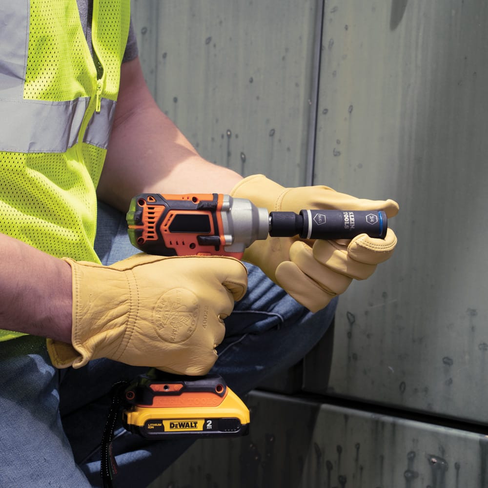 Lineman making final adjustments to the Klein 66080 2-in-1 flip impact socket mounted on a 1/2-inch impact wrench.