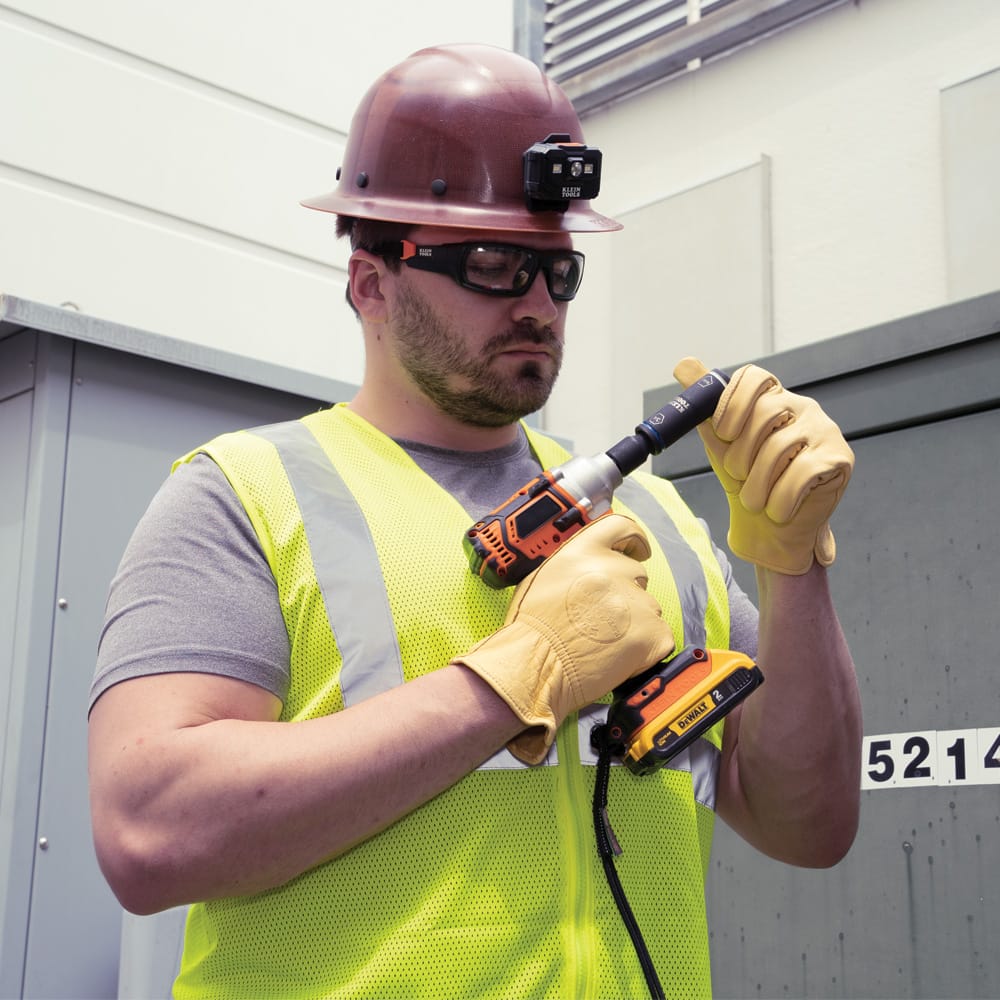 Utility worker checking the Klein 66080 flip socket size orientation on a 1/2-inch impact wrench before opening a pad-mounted electrical enclosure.
