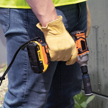 Utility worker holding a cordless impact wrench fitted with the Klein 66080 penta and hex flip socket ready for cabinet bolting.